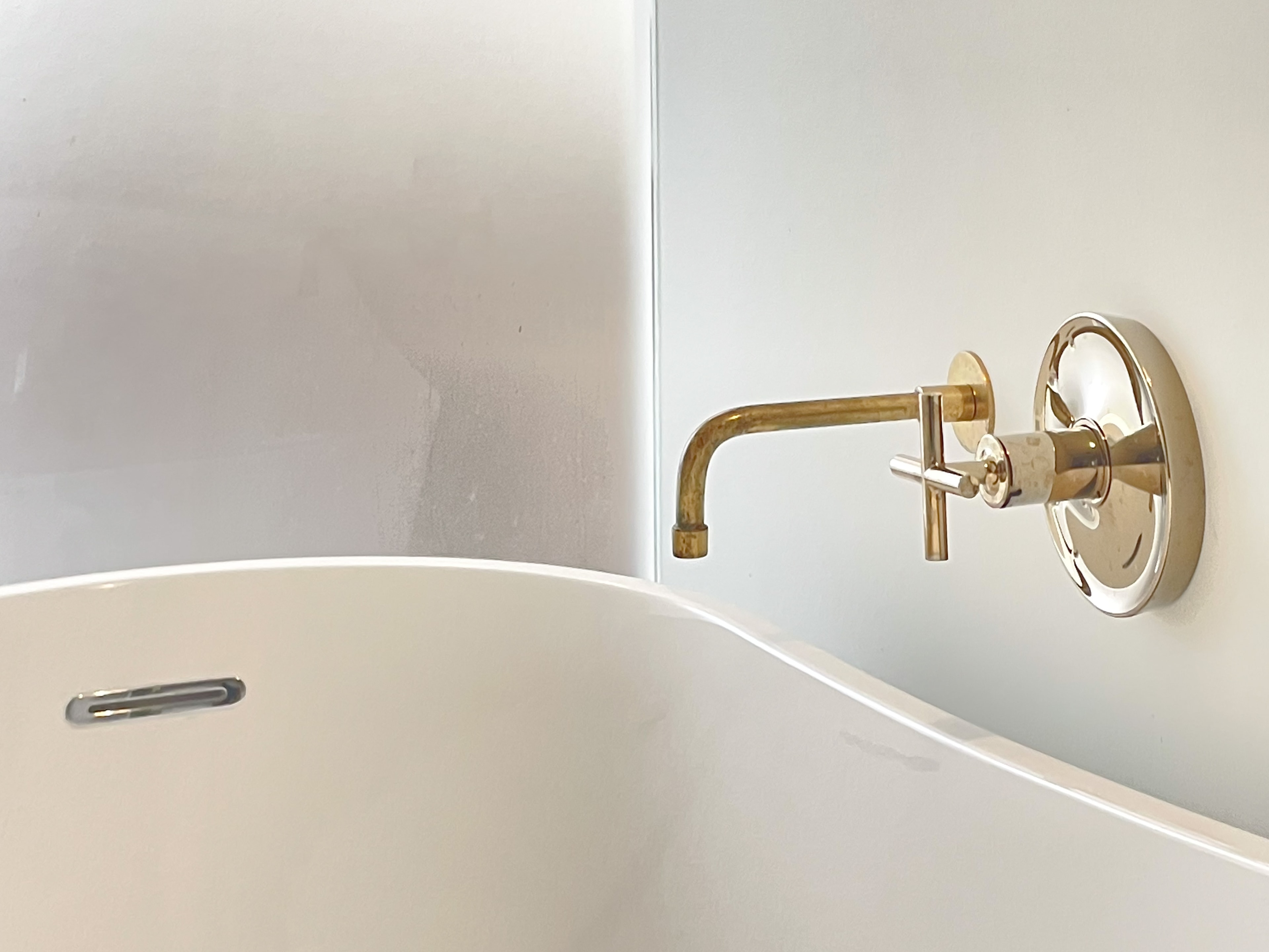 Detail of brass wall-mount tub faucet with cross-handle hardware