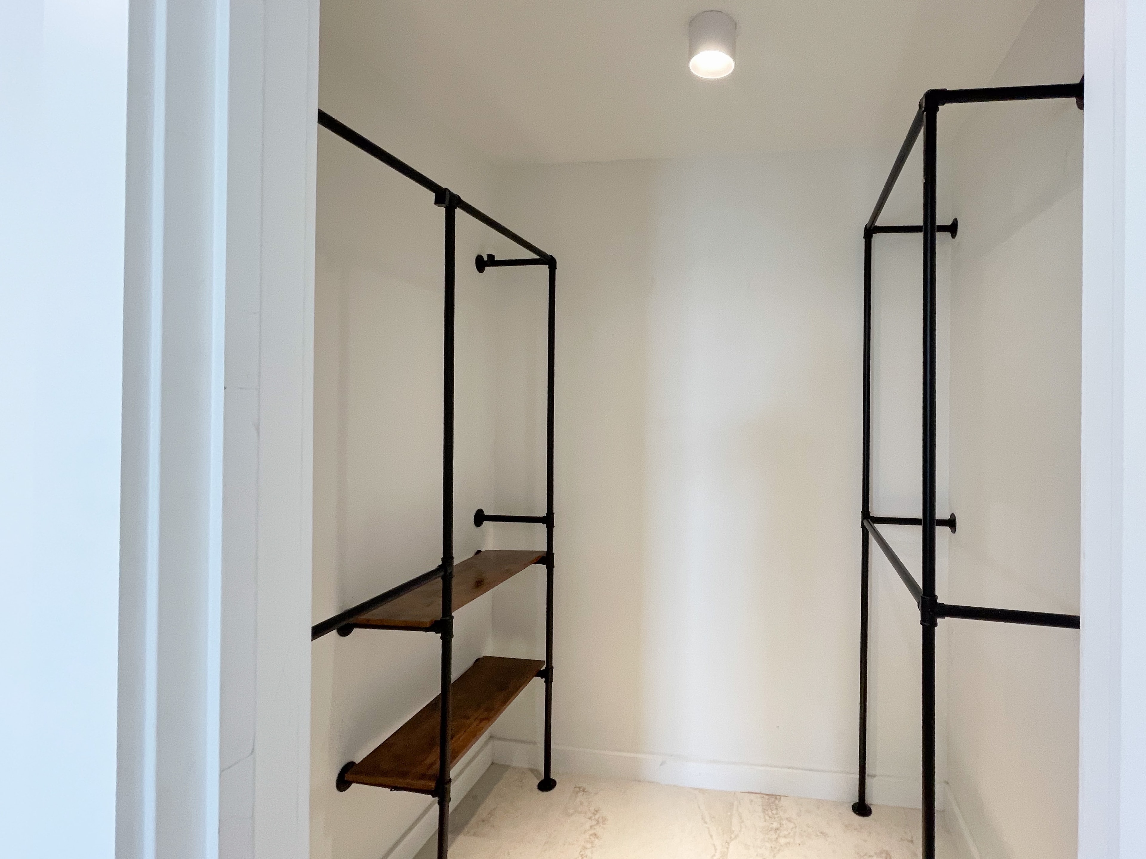 Custom walk-in closet with industrial pipe shelving and wood shelves