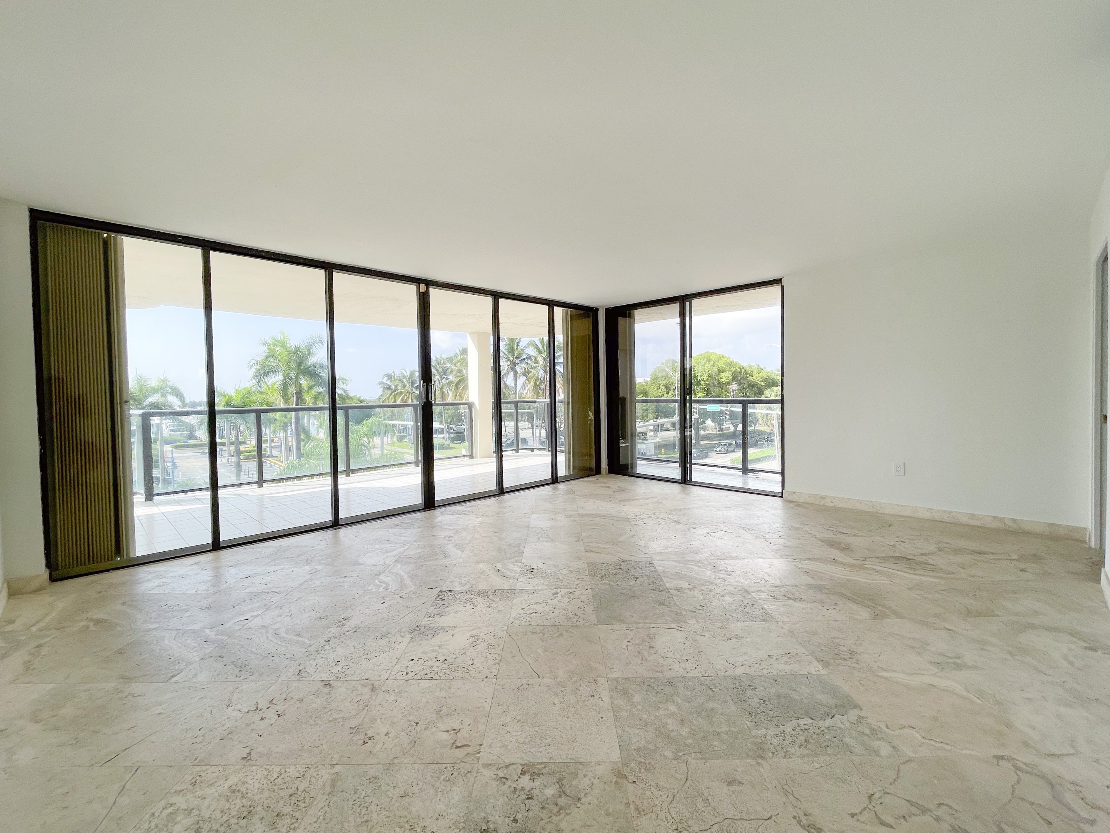 Spacious bedroom with marble floors and sliding glass door to balcony