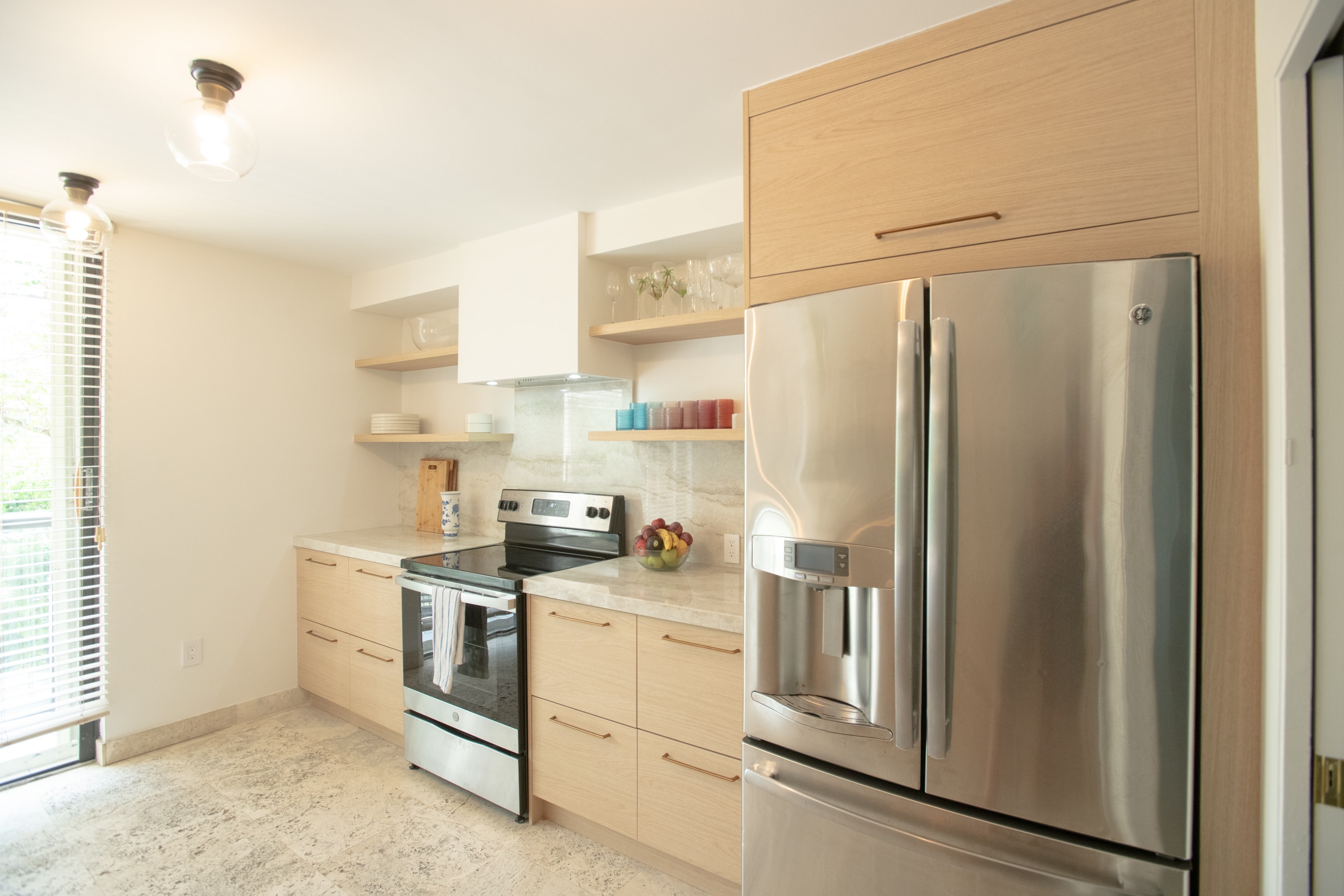 Kitchen with stainless steel French door refrigerator, range, and light wood cabinetry