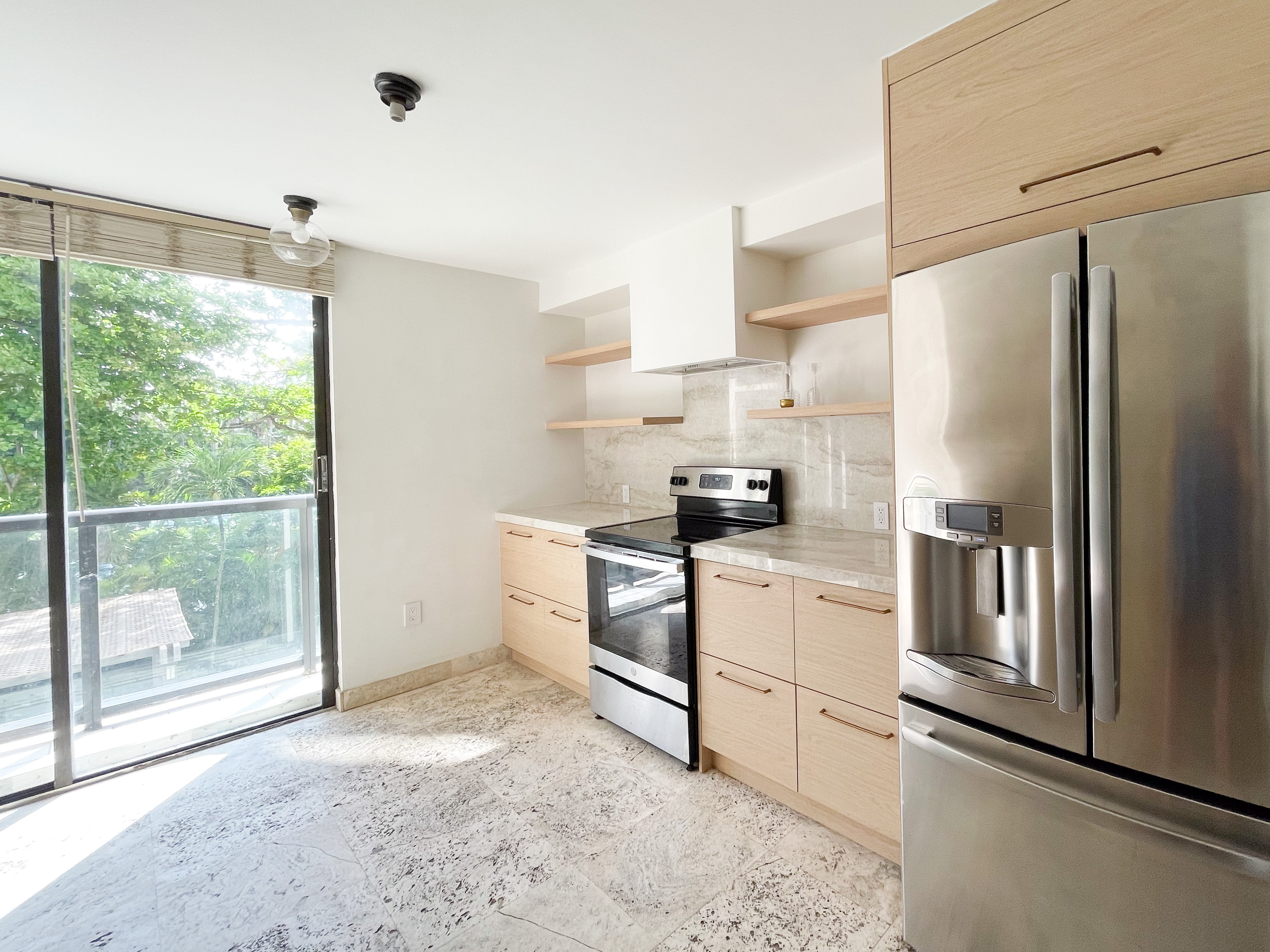 Kitchen with stainless range and open terrace view through sliding glass doors