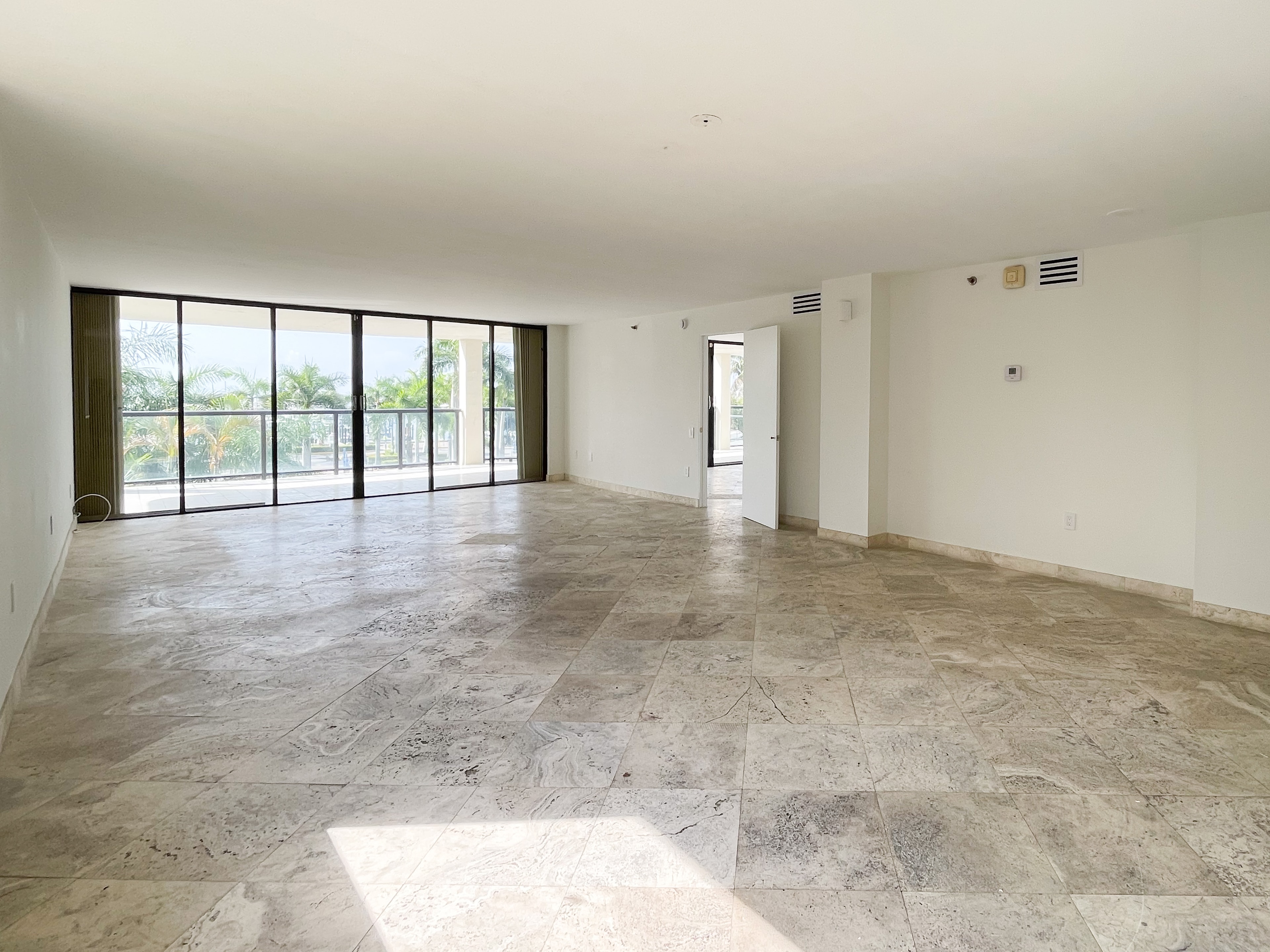Open living space with floor-to-ceiling sliding doors and palm views