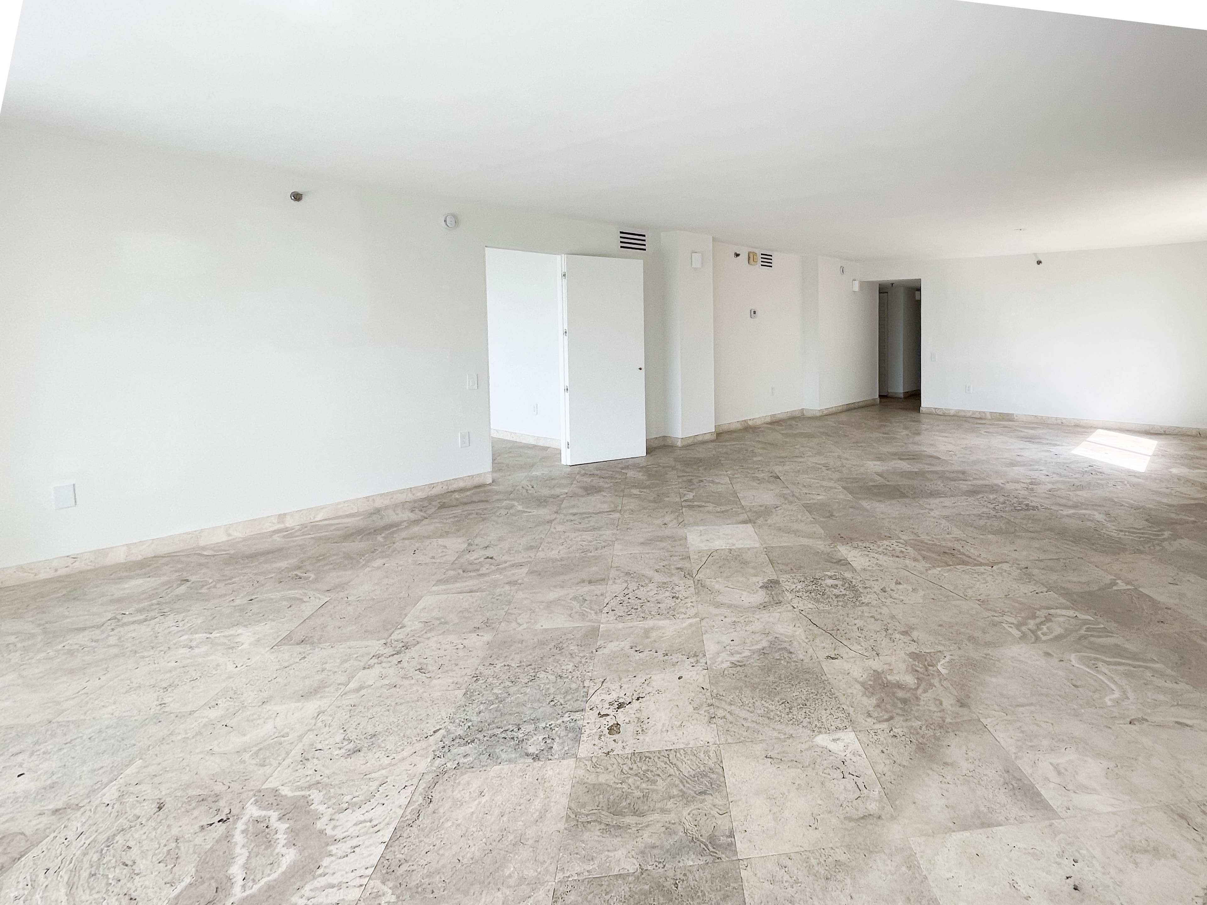 Spacious living area with travertine floors and white walls