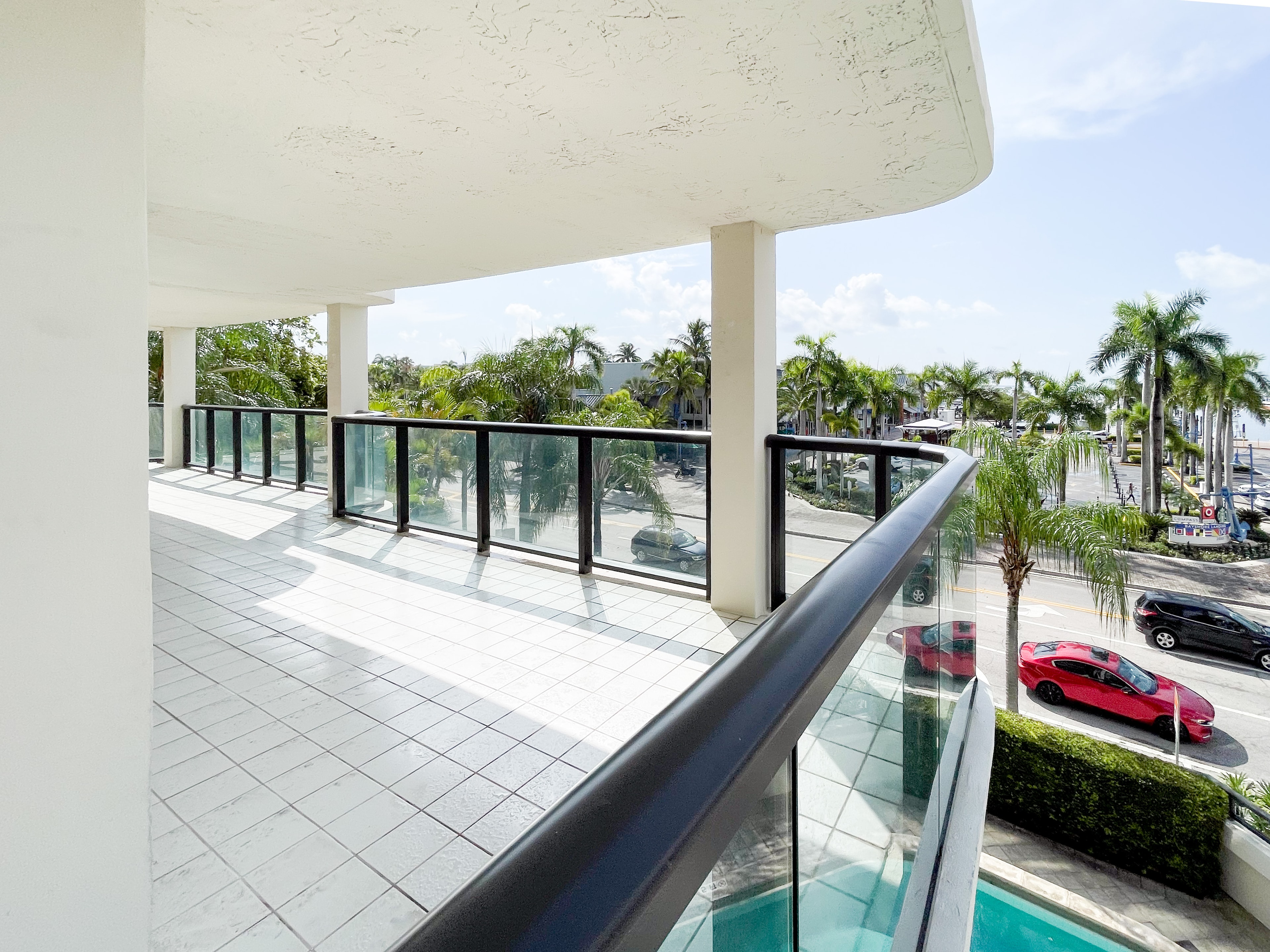 Corner terrace with glass railings overlooking palm-lined street