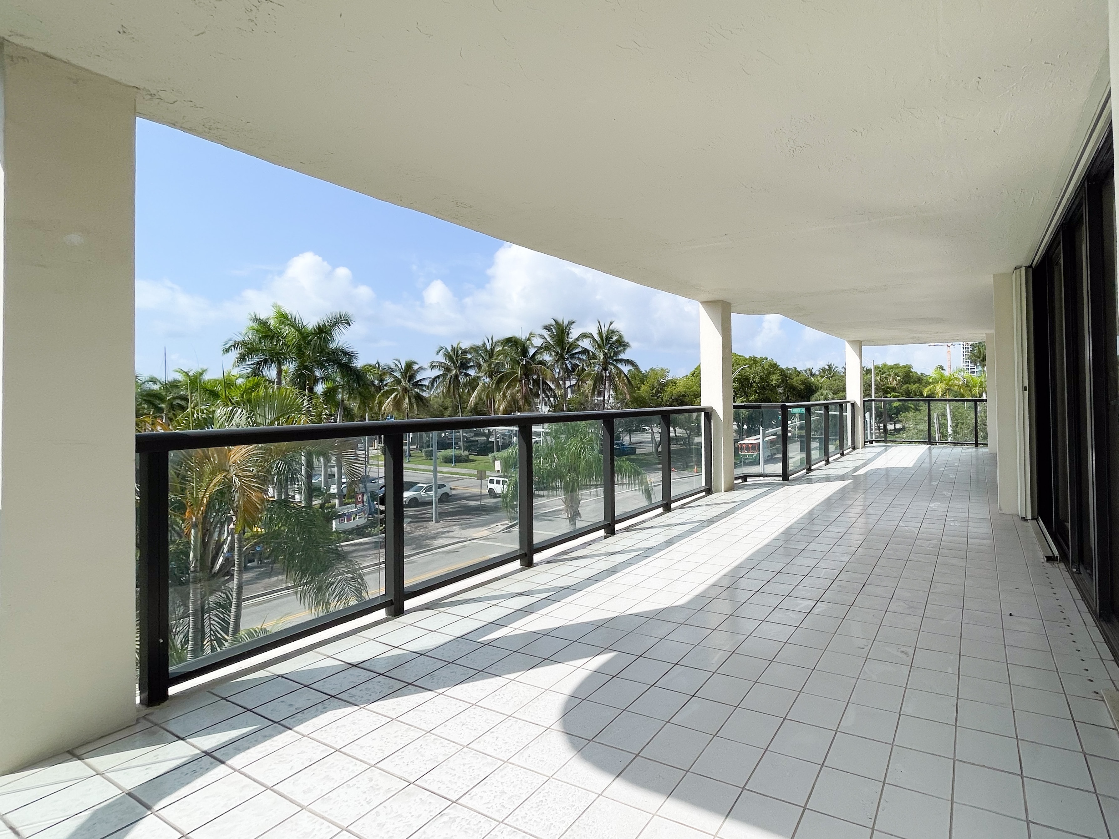 Expansive terrace with glass railings and palm tree views